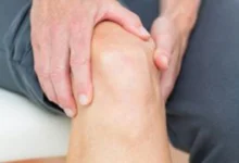 صورة توضيحية لشخص يطبق كمادة دافئة على مفصل الركبة لتخفيف الم الركبه والألم.