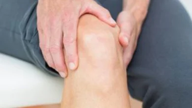 صورة توضيحية لشخص يطبق كمادة دافئة على مفصل الركبة لتخفيف الم الركبه والألم.