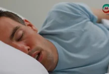 صورة تظهر شخصًا نائمًا على جانبه مع وجود بقعة لعاب على الوسادة، illustrating the concept of drooling during sleep.