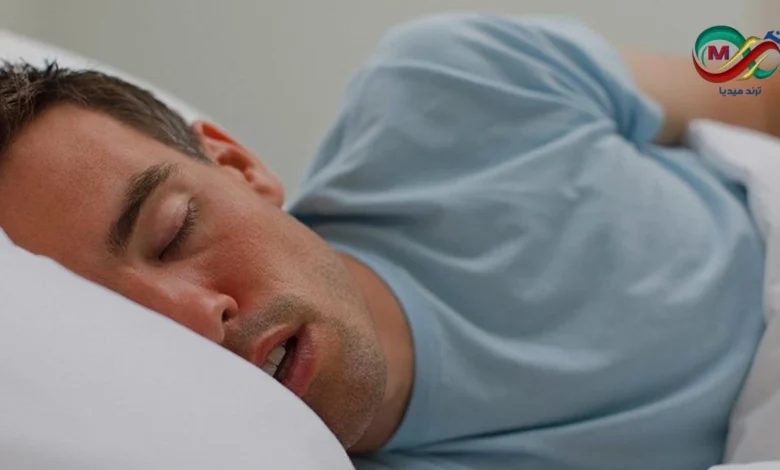 صورة تظهر شخصًا نائمًا على جانبه مع وجود بقعة لعاب على الوسادة، illustrating the concept of drooling during sleep.
