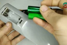 صورة توضيحية تظهر ريموت تلفزيون مفتوح مع أسطوانات من ورق الألمنيوم موضوعة مكان البطاريات.
