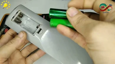 صورة توضيحية تظهر ريموت تلفزيون مفتوح مع أسطوانات من ورق الألمنيوم موضوعة مكان البطاريات.