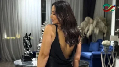 صورة للفنانة بوسي ترتدي فستان أسود طويل مكشوف الظهر مع شعر منسدل على الكتفين خلال جلسة تصوير احترافية.