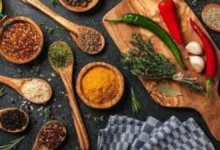 مكونات طبيعية من المطبخ تمثل العلاقة بين التوابل والسرطان مثل الكمون والزعتر والقرفة على طاولة خشبية