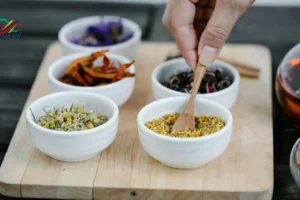 مجموعة متنوعة من الأعشاب الطبيعية في أكواب وأطباق صغيرة، تمثل أعشاب لتقوية الذاكرة والتركيز مثل الجنكة والروزماري والميرمية