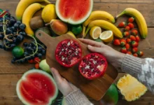 طبق يحتوي على تشكيلة فواكه حمراء طازجة تبرز فوائد الفواكه الحمراء للقلب مثل الرمان والفراولة والتوت.