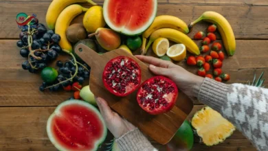 طبق يحتوي على تشكيلة فواكه حمراء طازجة تبرز فوائد الفواكه الحمراء للقلب مثل الرمان والفراولة والتوت.
