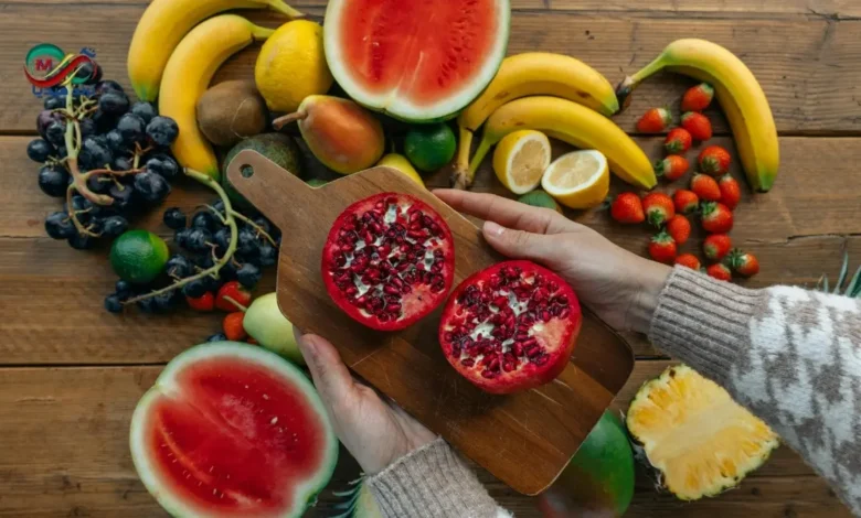 طبق يحتوي على تشكيلة فواكه حمراء طازجة تبرز فوائد الفواكه الحمراء للقلب مثل الرمان والفراولة والتوت.